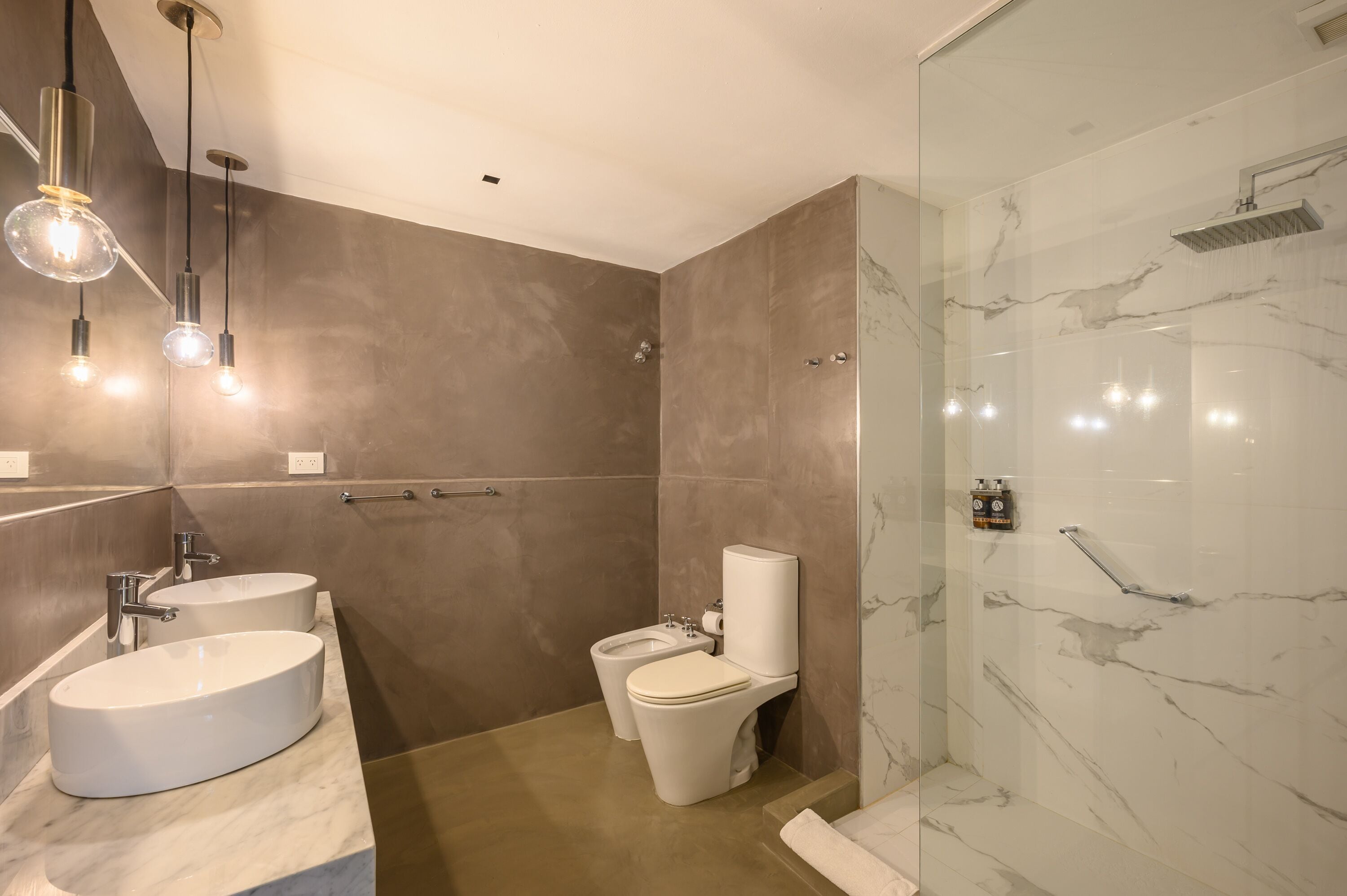 Un bany modern amb dues dutxes, un vàter i una cabina de vidre.