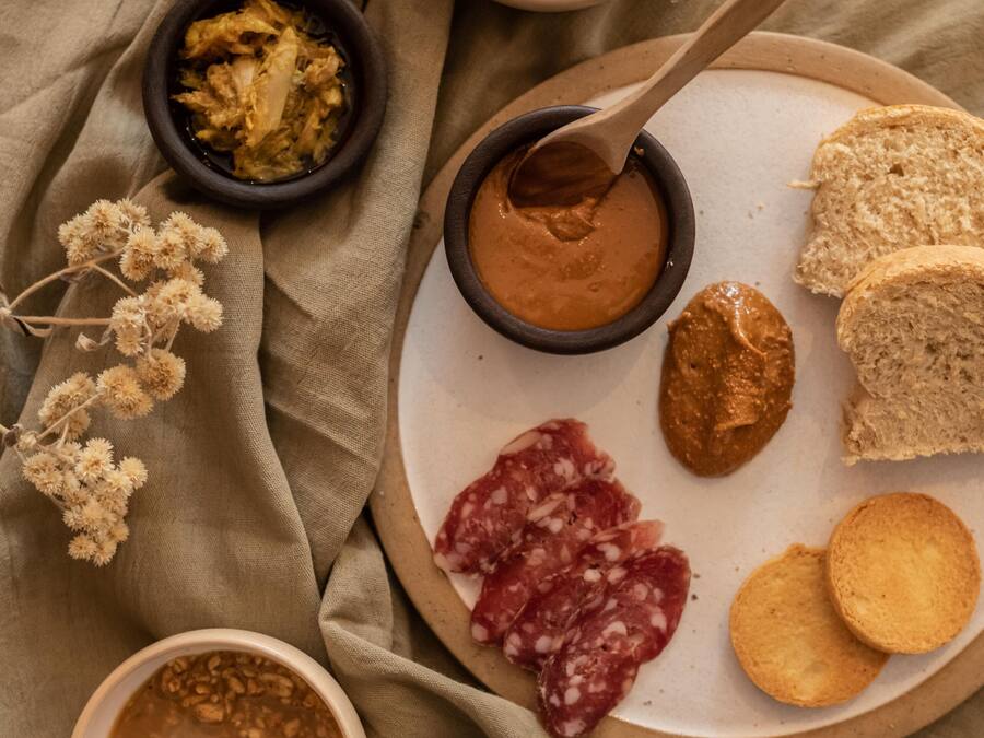 A plate with various food items, including bread, crackers, and a spread, on a cloth surface.