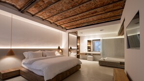 A modern bedroom with a wooden bed, a large mirror, and a built-in bench. - Azur Real Hotel Boutique & Spa (Córdoba)