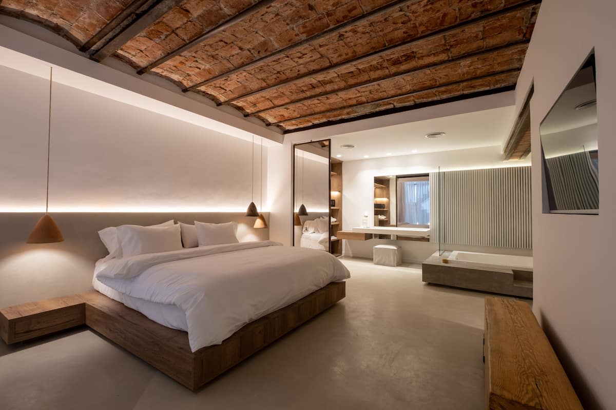 A modern bedroom with a wooden bed, a large mirror, and a built-in bench.