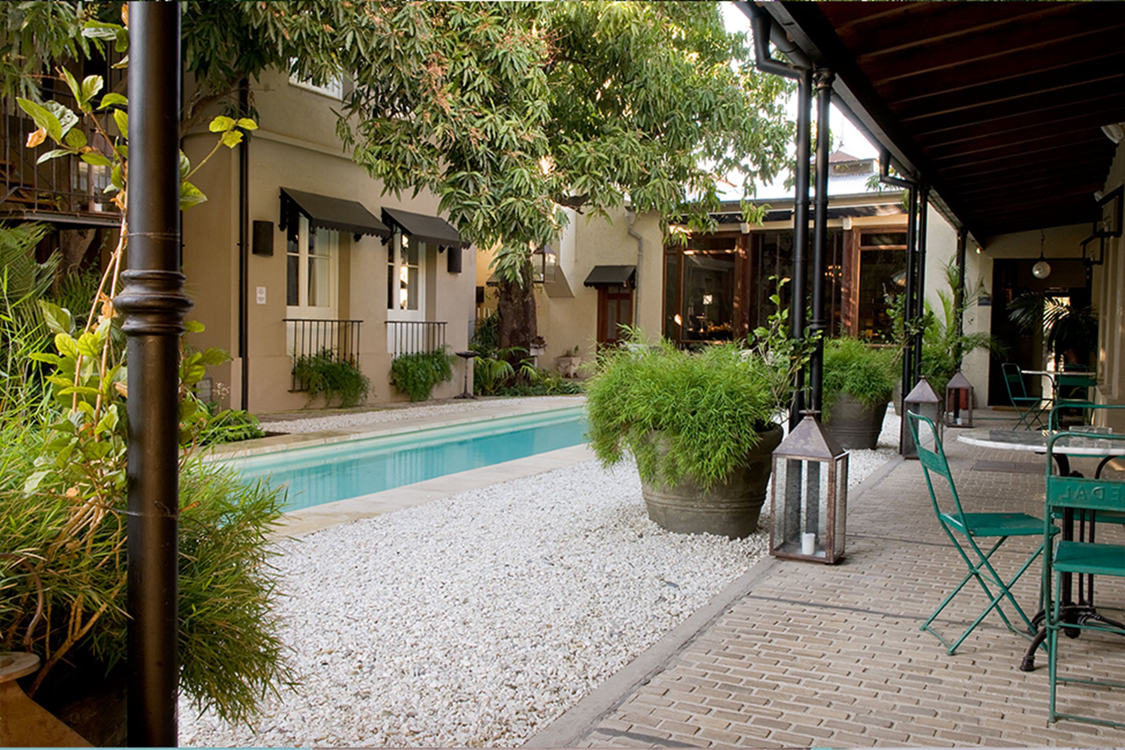 A courtyard with a swimming pool, potted plants, and outdoor seating.