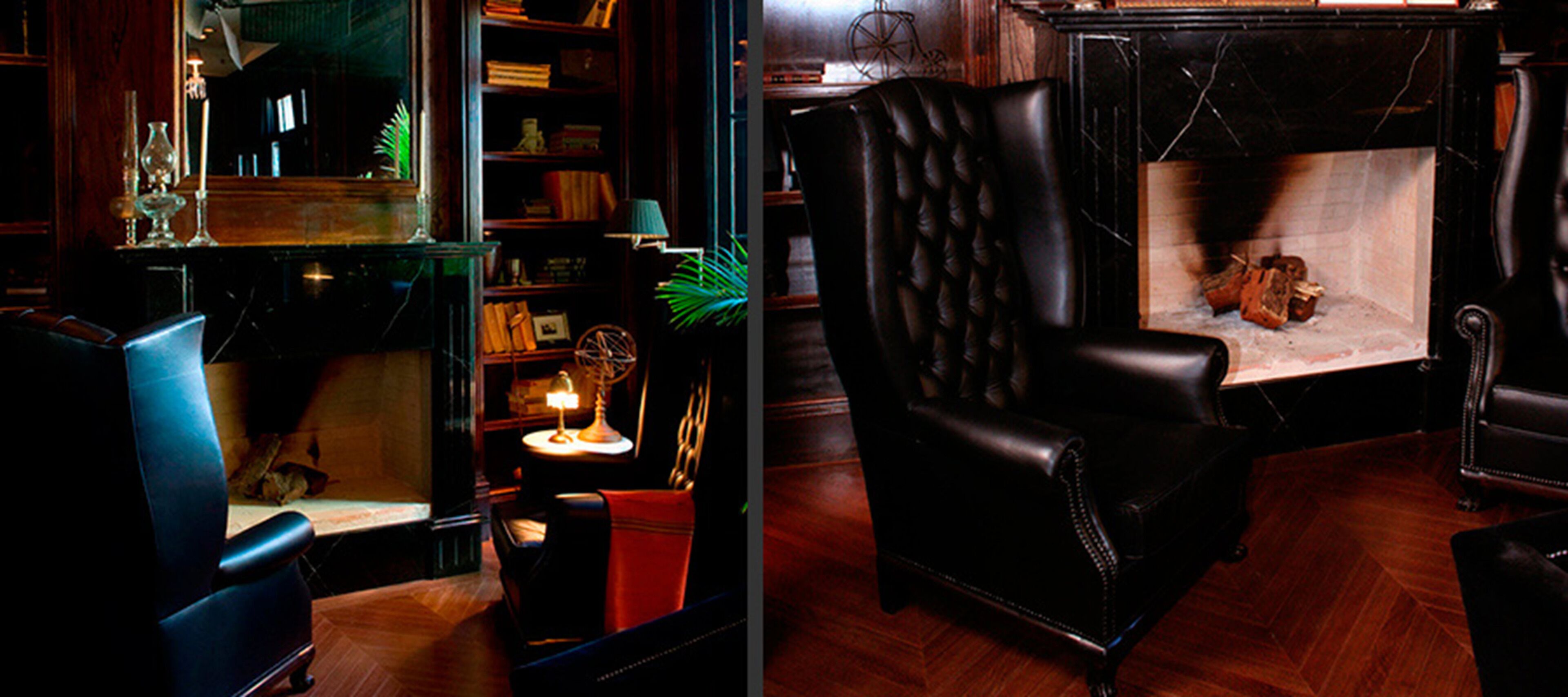 Una habitación con un sillón de cuero, chimenea, estantería y espejo.