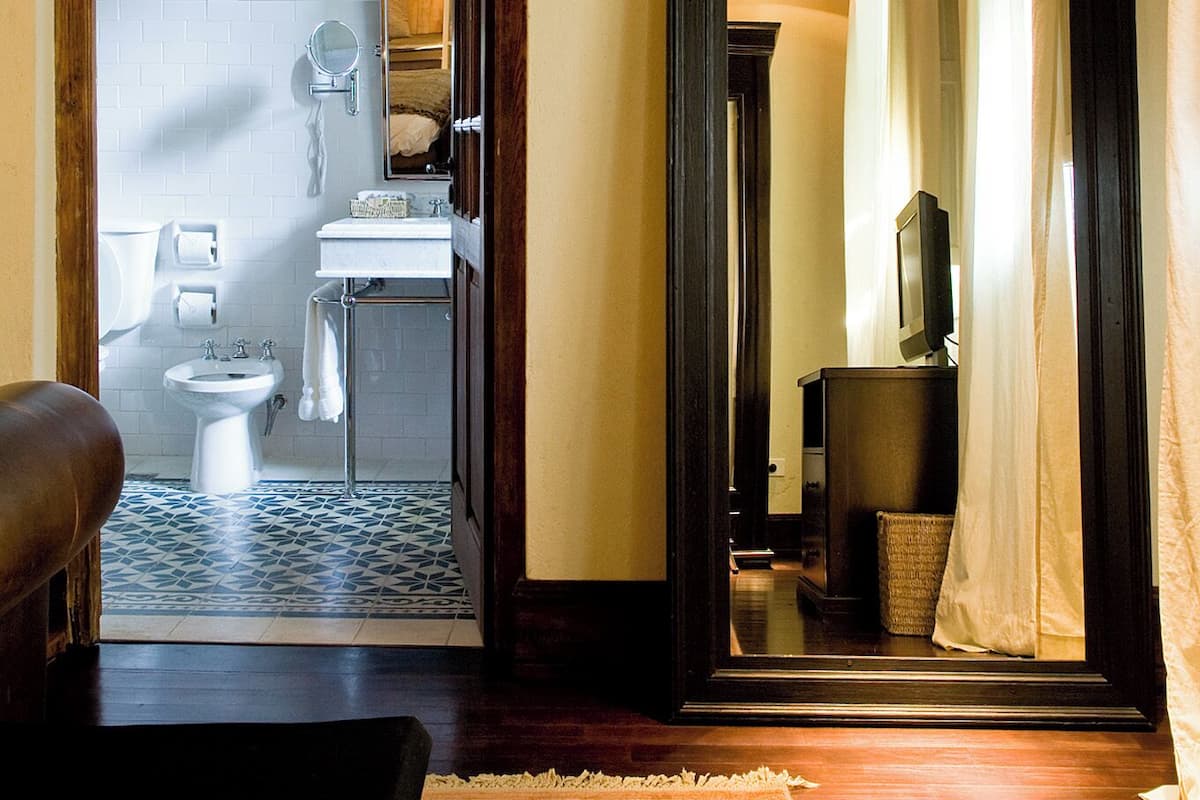 A bathroom with a toilet, sink, and mirror.