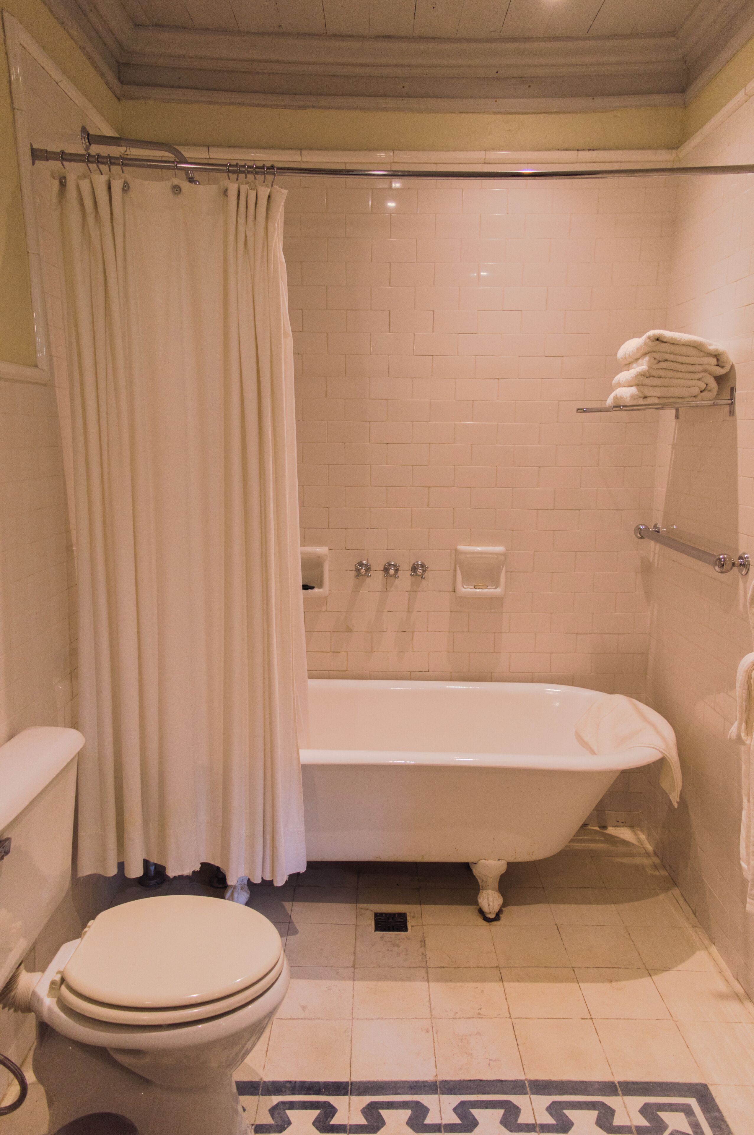 A bathroom with a bathtub, toilet, and a shower curtain.