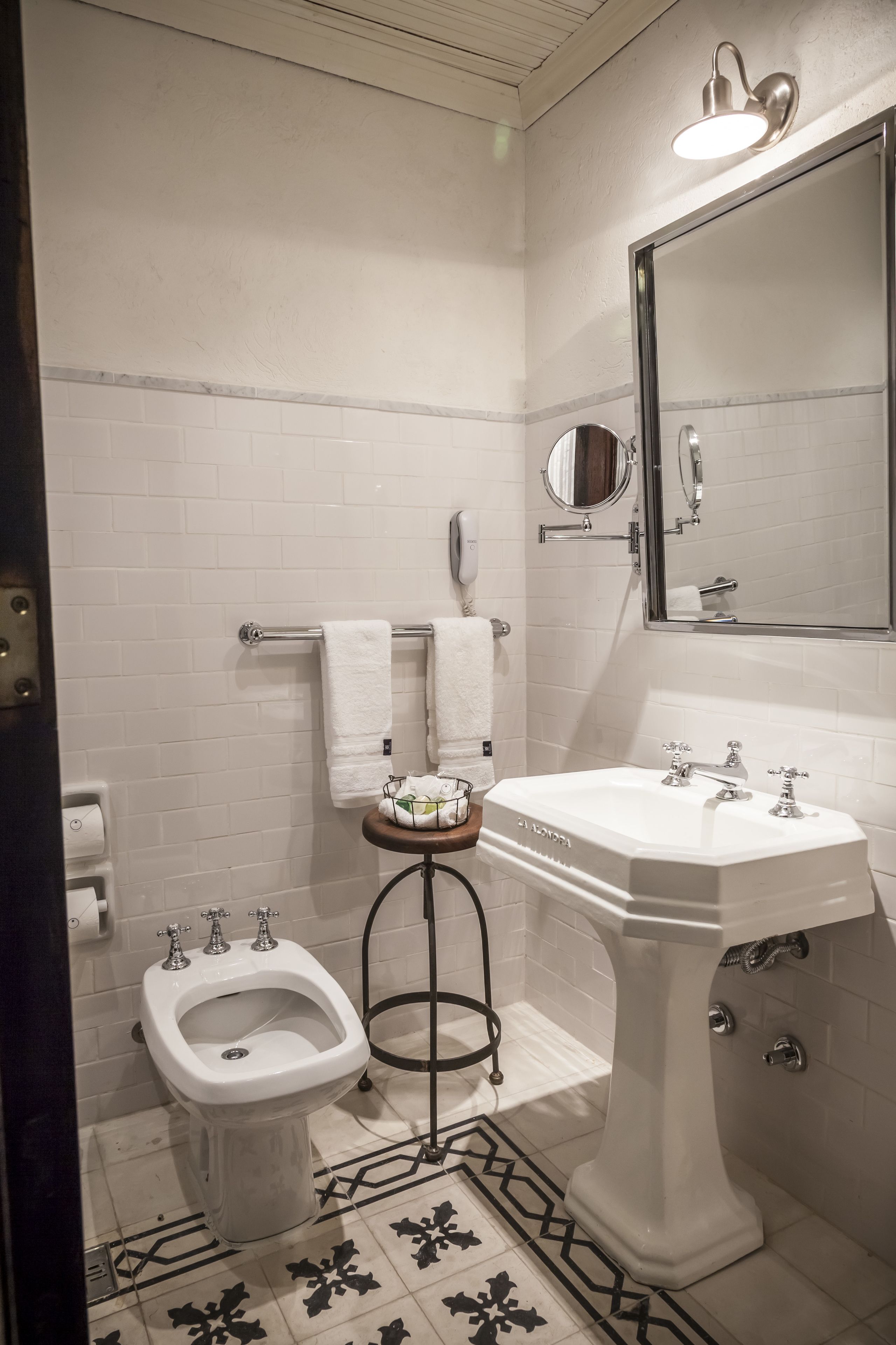 Une salle de bain avec un lavabo sur colonne blanc, un bidet, un porte-serviettes et un miroir.