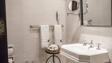 Une salle de bain avec un lavabo sur colonne blanc, un bidet, un porte-serviettes et un miroir.