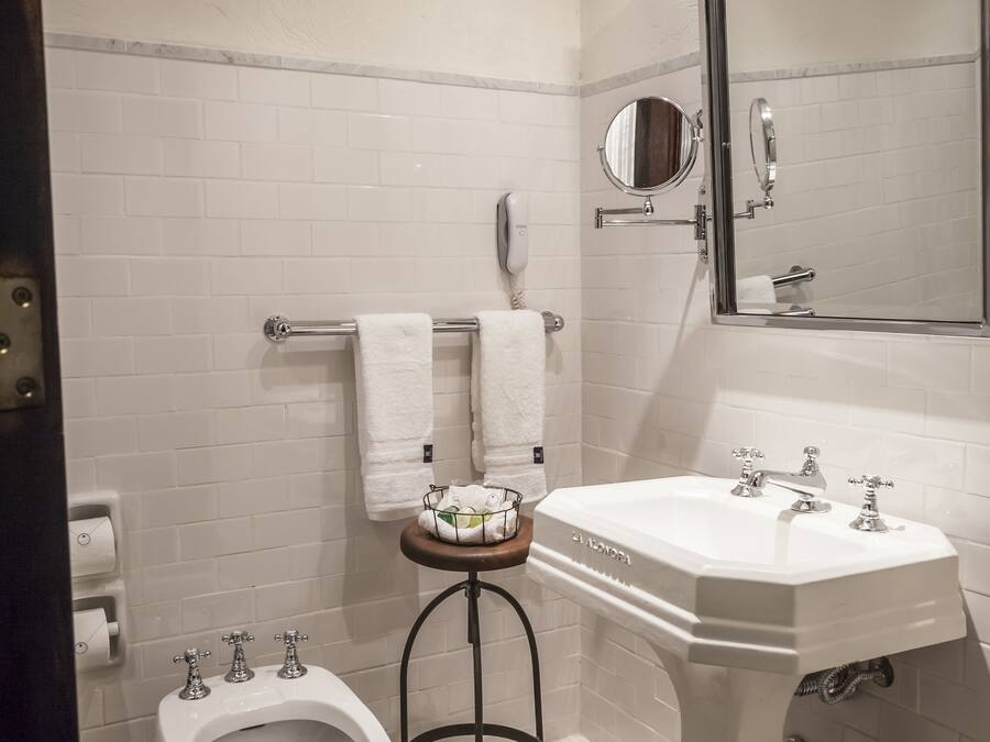 Une salle de bain avec un lavabo sur colonne blanc, un bidet, un porte-serviettes et un miroir.