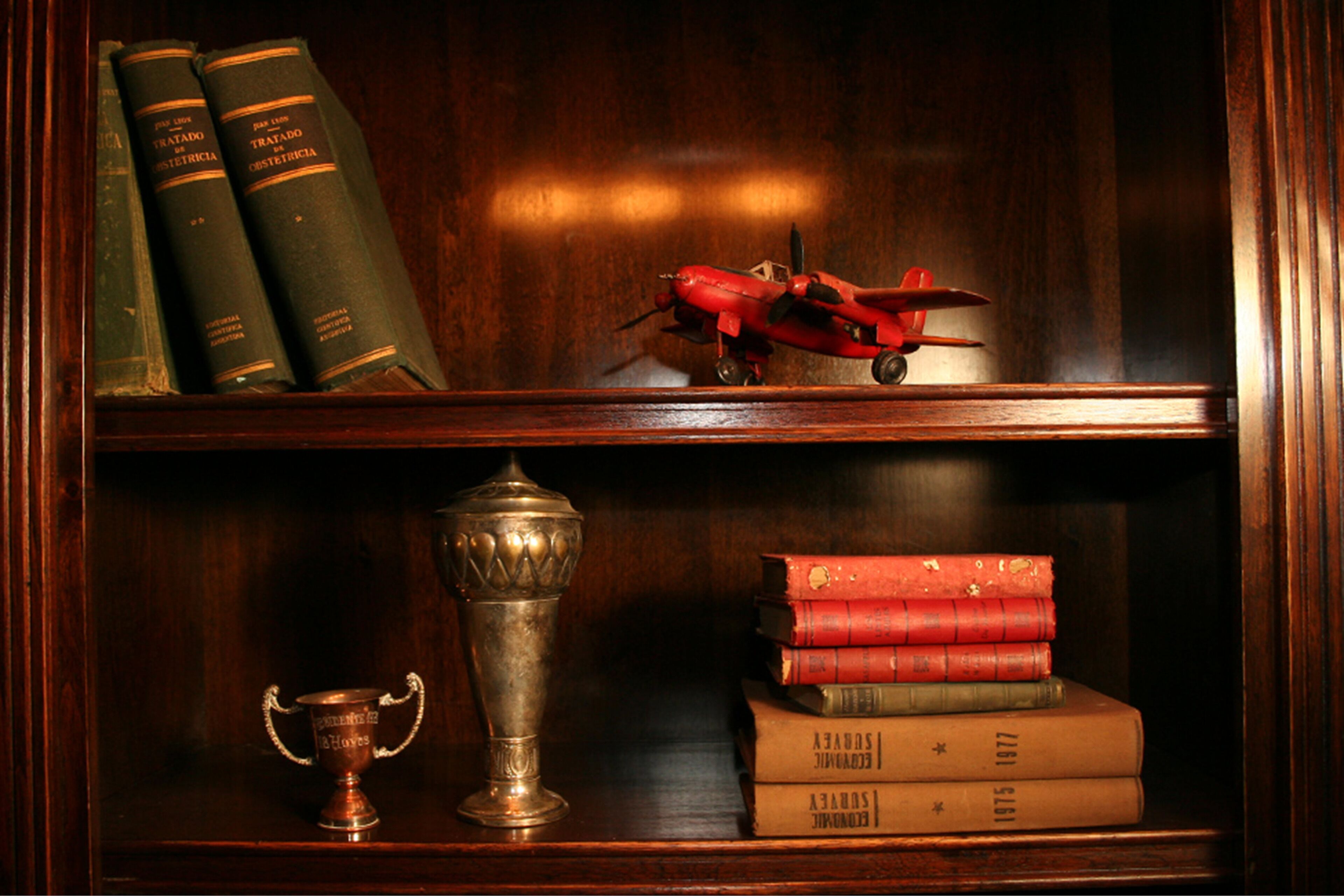 Une bibliothèque en bois avec des livres et un trophée.
