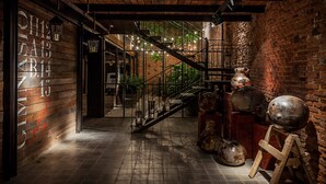 Een rustiek interieur met onbehandelde bakstenen muren, een houten vloer en een trap naar een balkon.