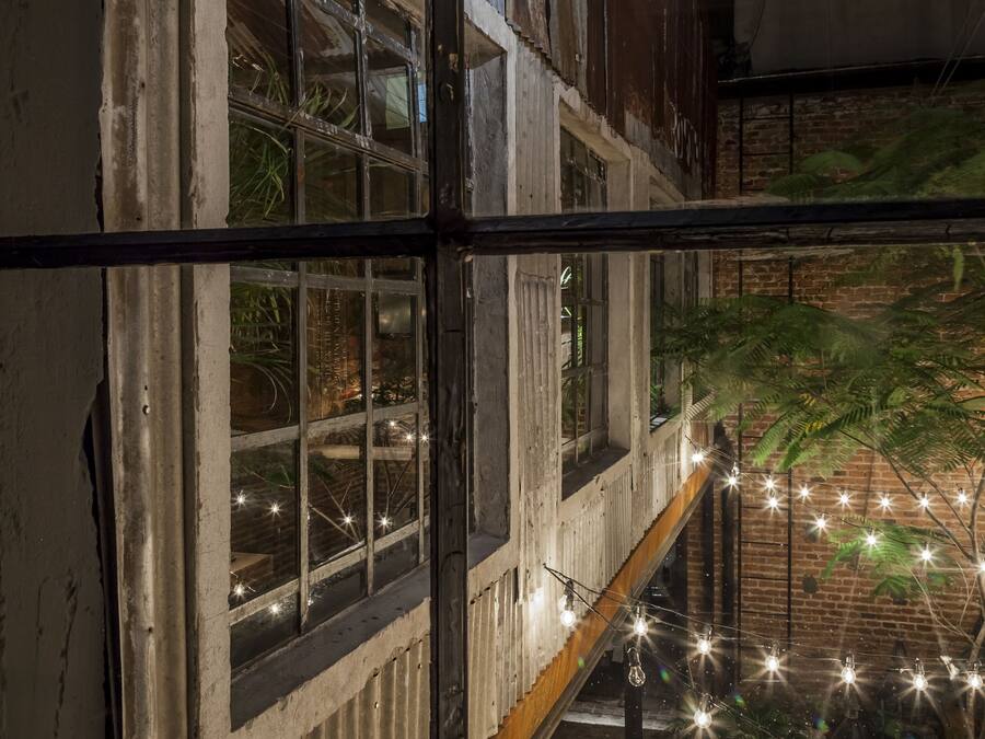 A view from a window with metal bars, looking out to a balcony with string lights and plants.
