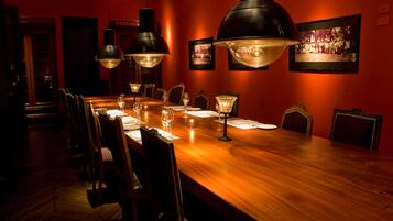 Una larga mesa de comedor de madera con sillas, iluminada por tres grandes lámparas colgantes.