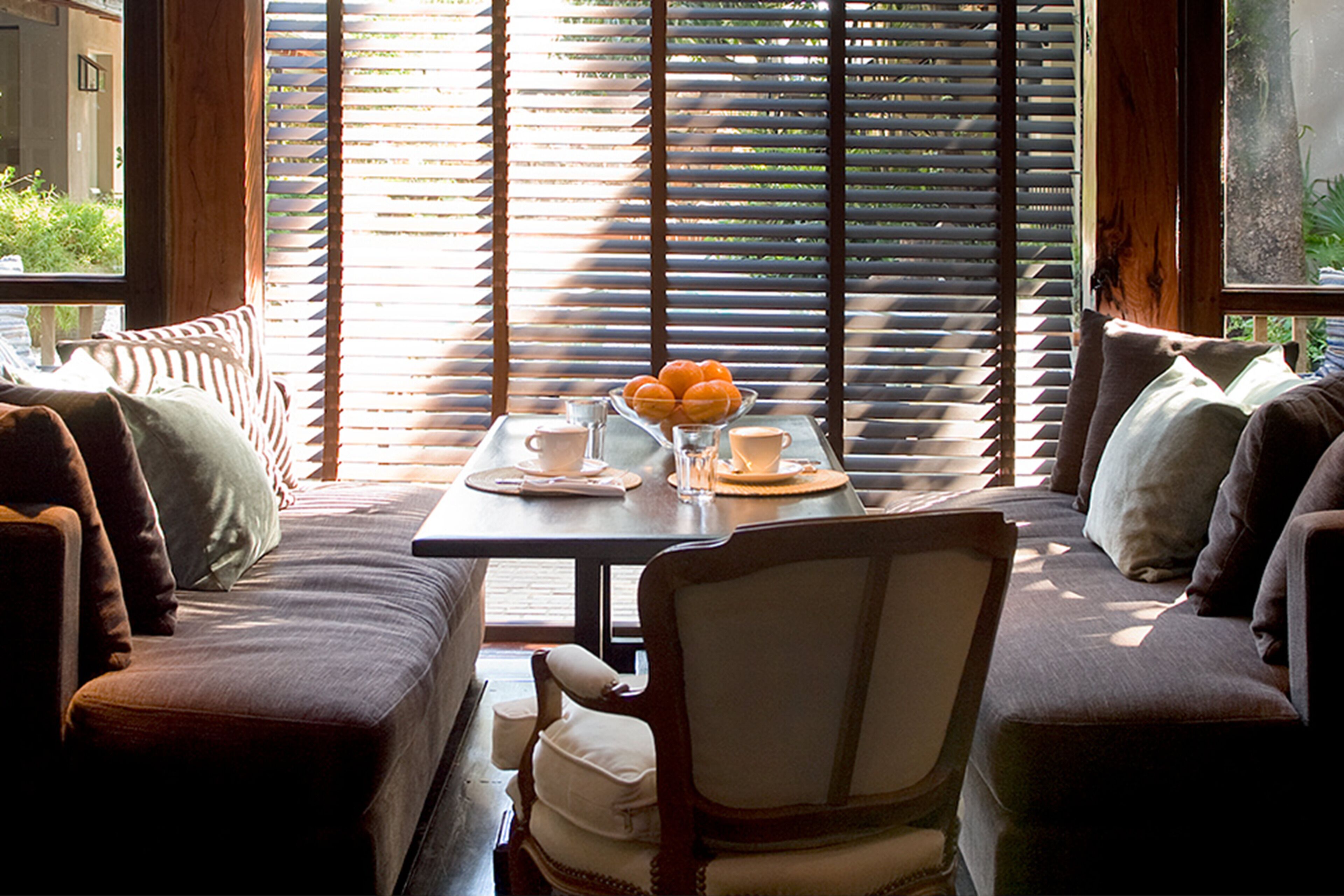 A cozy seating area with a table set for breakfast, featuring a bowl of fruit, cups, and a glass of water.