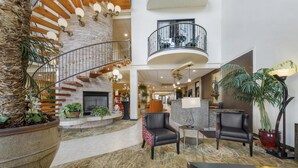 A spacious lobby with a stone wall, a spiral staircase, and a large potted plant. - Best Western Plus Swiss Chalet Hotel & Suites (Pecos)