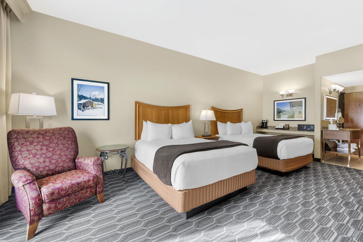 Een hotelkamer met twee bedden, een stoel, een tafeltje en een spiegel.