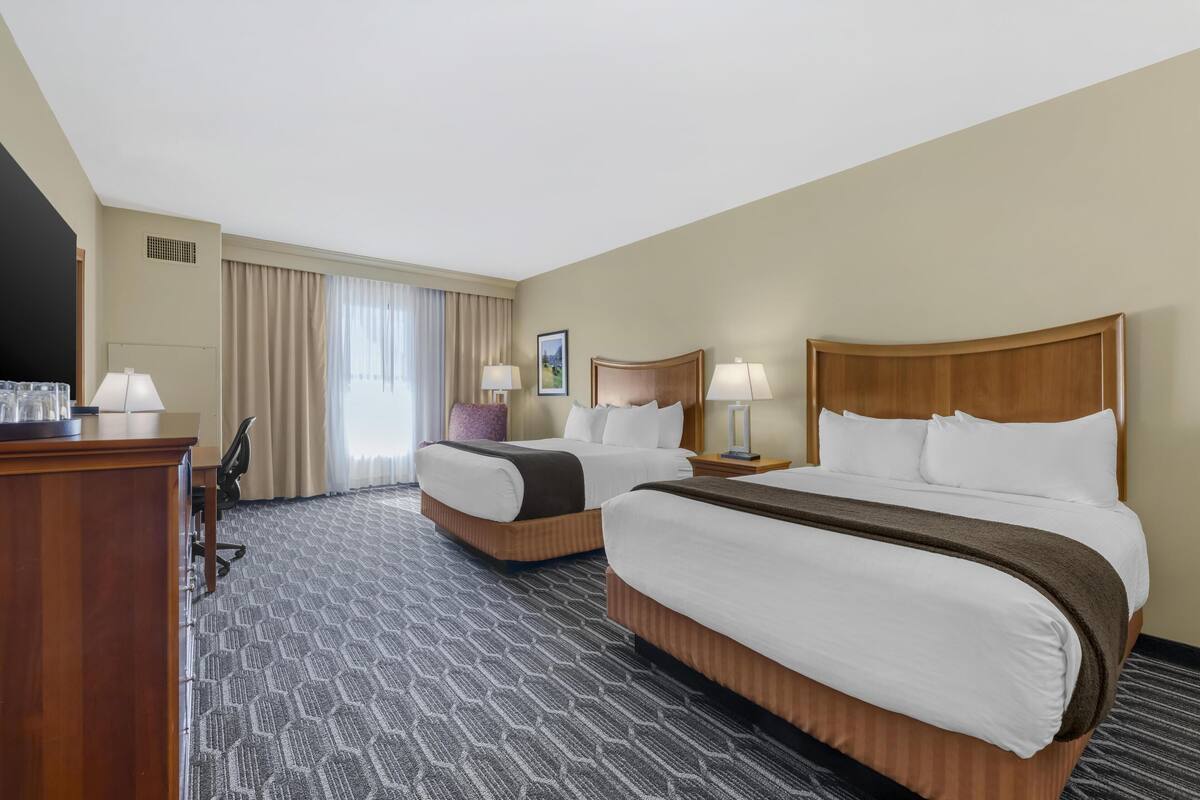 Een hotelkamer met twee bedden, een bureau en een stoel.