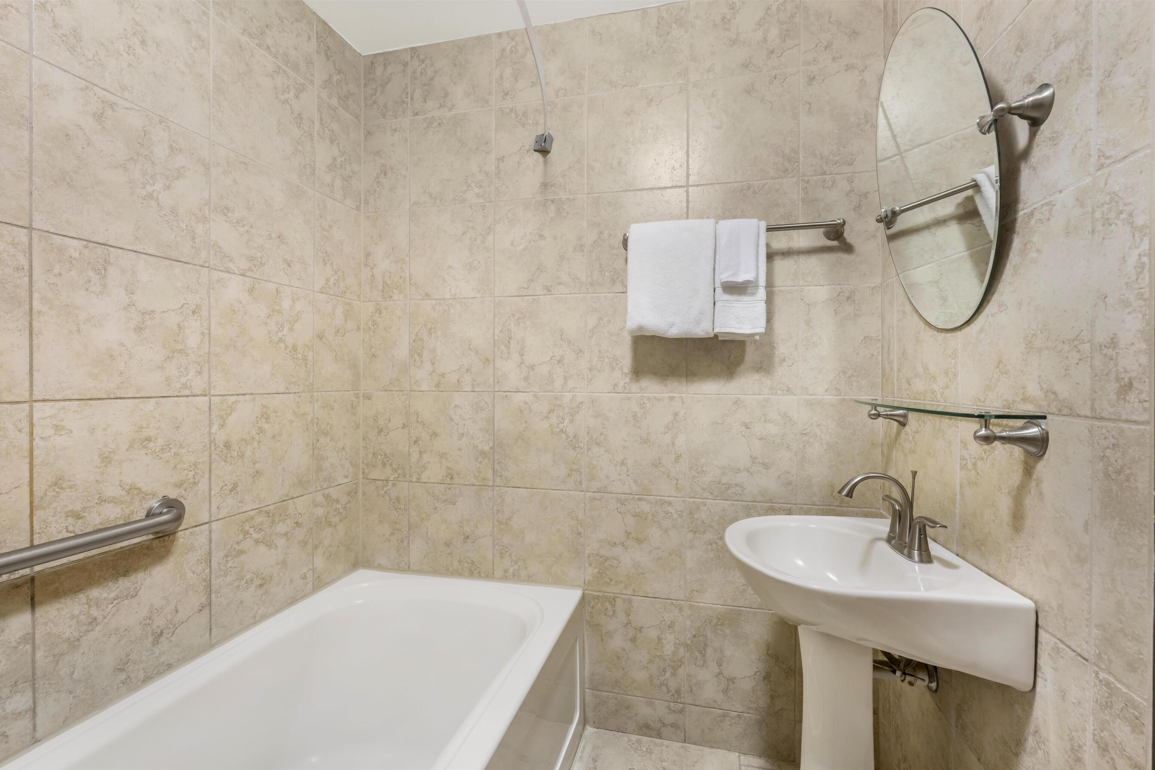Une salle de bain équipée d’une baignoire, d’un lavabo, d’un miroir et d’un porte-serviettes.