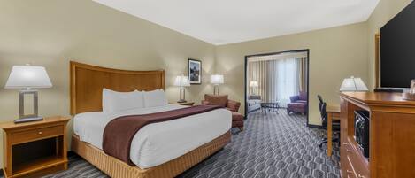 A hotel room with a large bed, two bedside tables with lamps, a desk with a chair, a television, and a mirror.