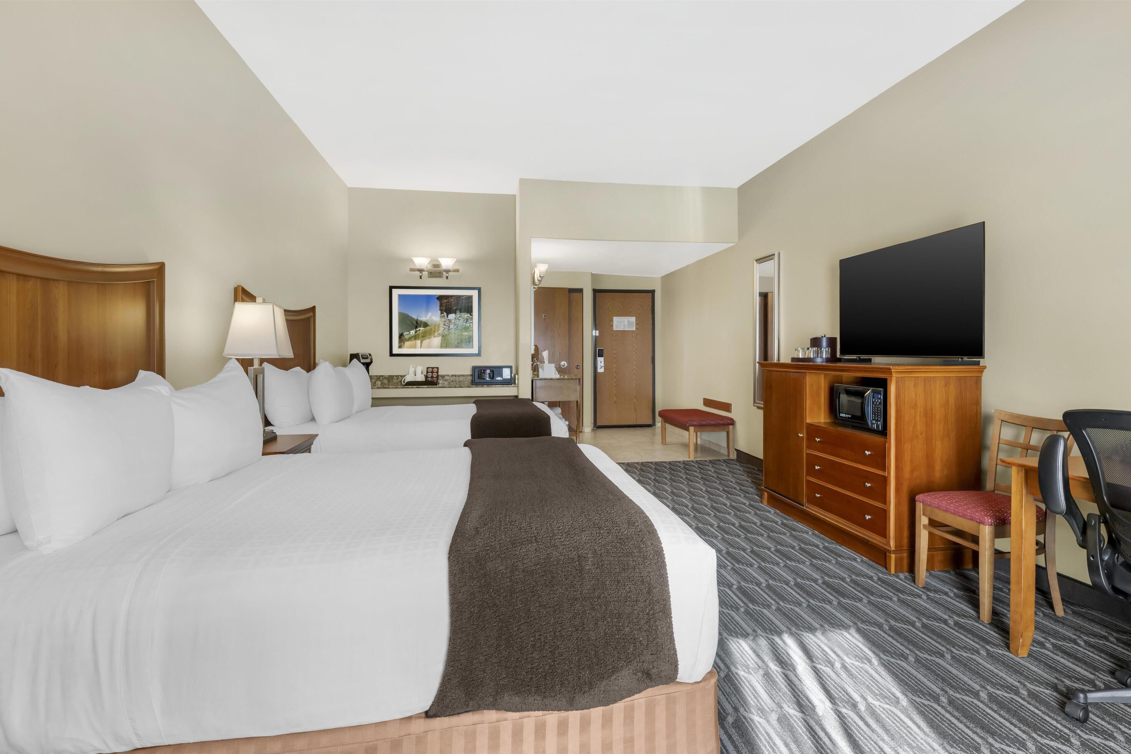 A hotel room with a large bed, a desk with a computer, a television, and a microwave.