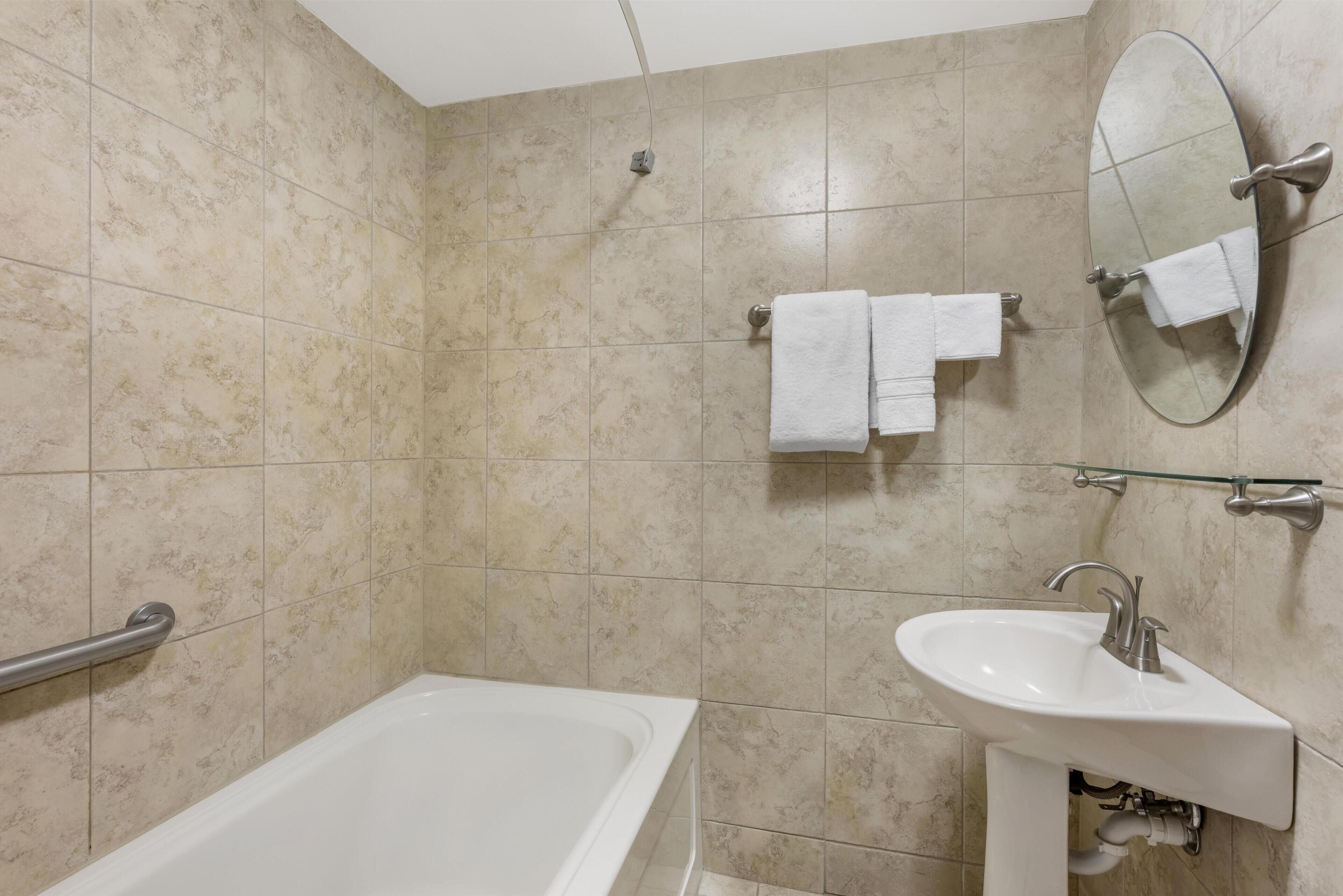 Un baño con bañera, lavabo y espejo.