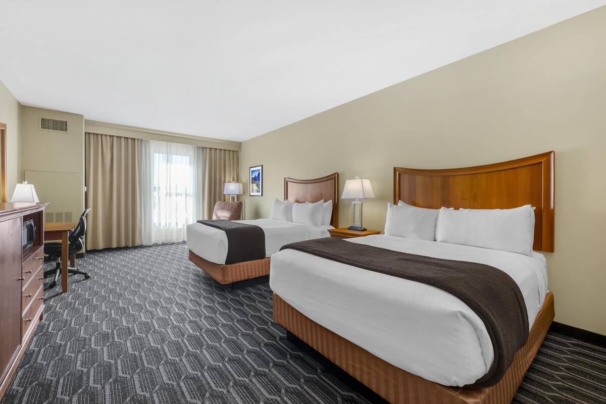 Een hotelkamer met twee bedden, een bureau en een stoel.