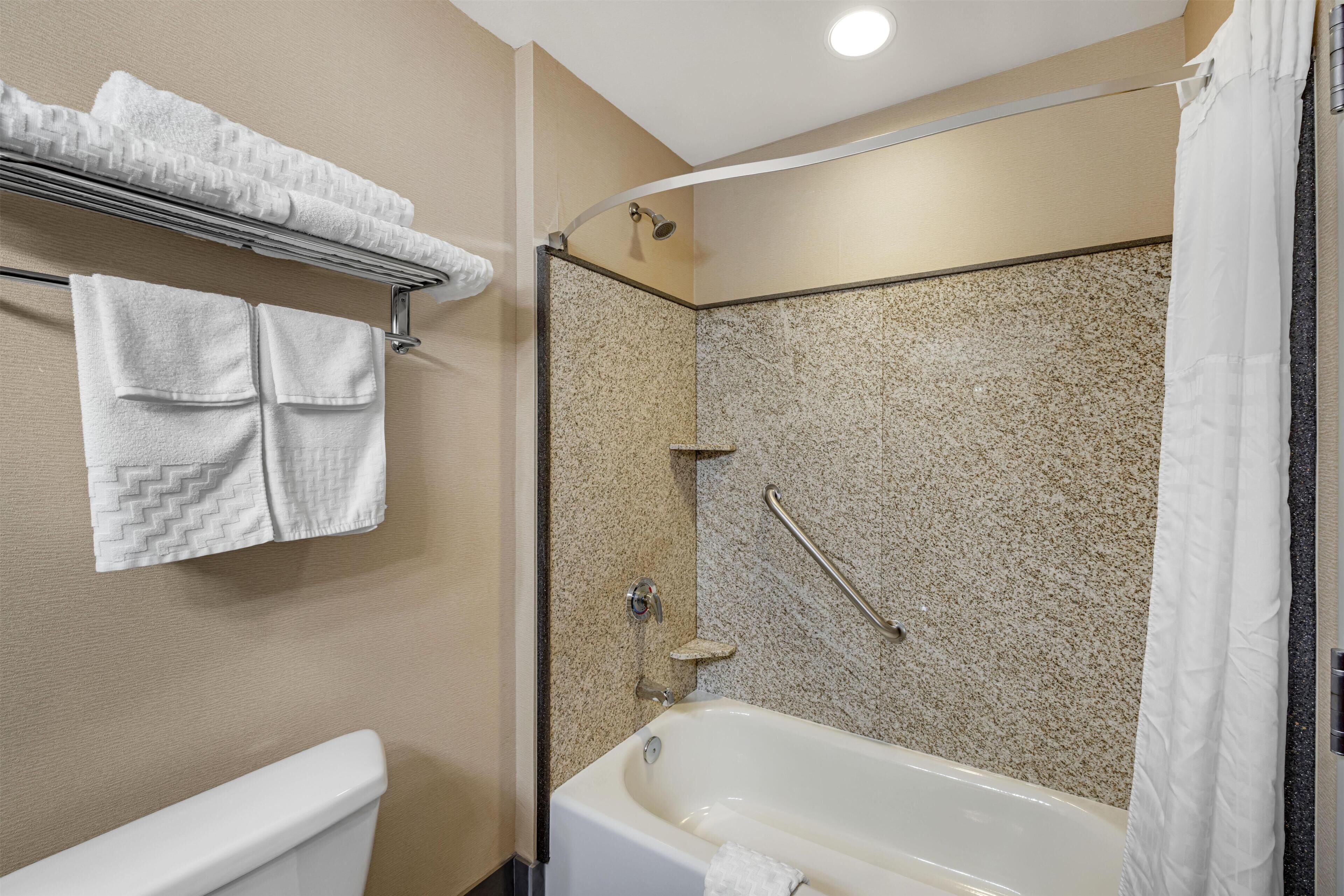 Une salle de bain équipée d’une baignoire, d’une douche, de toilettes et d’un porte-serviettes avec des serviettes pliées.