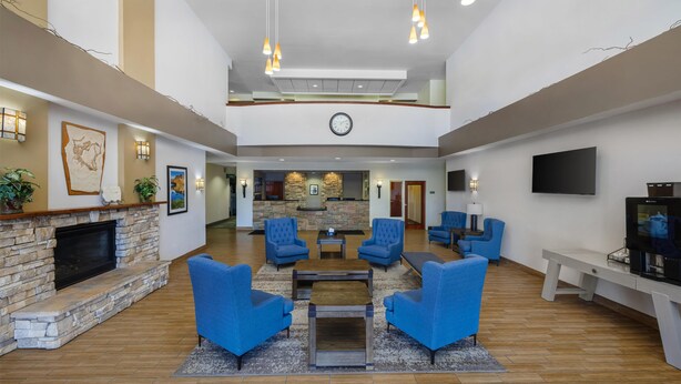 A spacious lobby with a stone fireplace, blue seating, a clock, and a flat-screen TV.