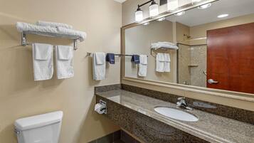 A bathroom with a toilet, sink, mirror, towel rack, and shower.