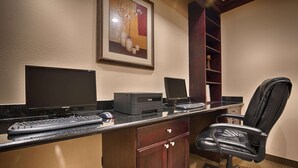 A hotel office with a desktop computer, a printer, a chair, and a bookshelf. - Best Western Plus Manvel Inn & Suites (Manvel)
