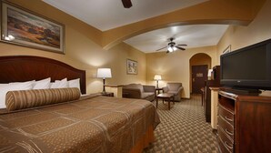 A hotel room with a large bed, a sofa, a TV, and a ceiling fan. - Best Western Plus Manvel Inn & Suites (Manvel)