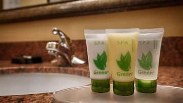 Three green bottles of Green spa conditioner and shampoo on a countertop.