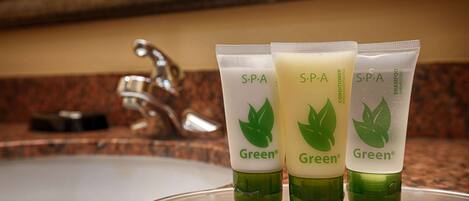 Three green bottles of Green spa conditioner and shampoo on a countertop.