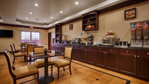 A hotel dining area with a buffet setup, a television, and a window with a view. - Best Western Plus Manvel Inn & Suites (Manvel)