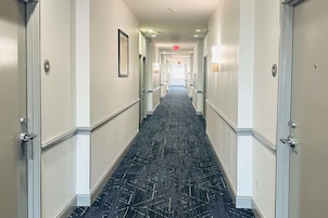 Un pasillo de hotel con suelo alfombrado y puertas a ambos lados.