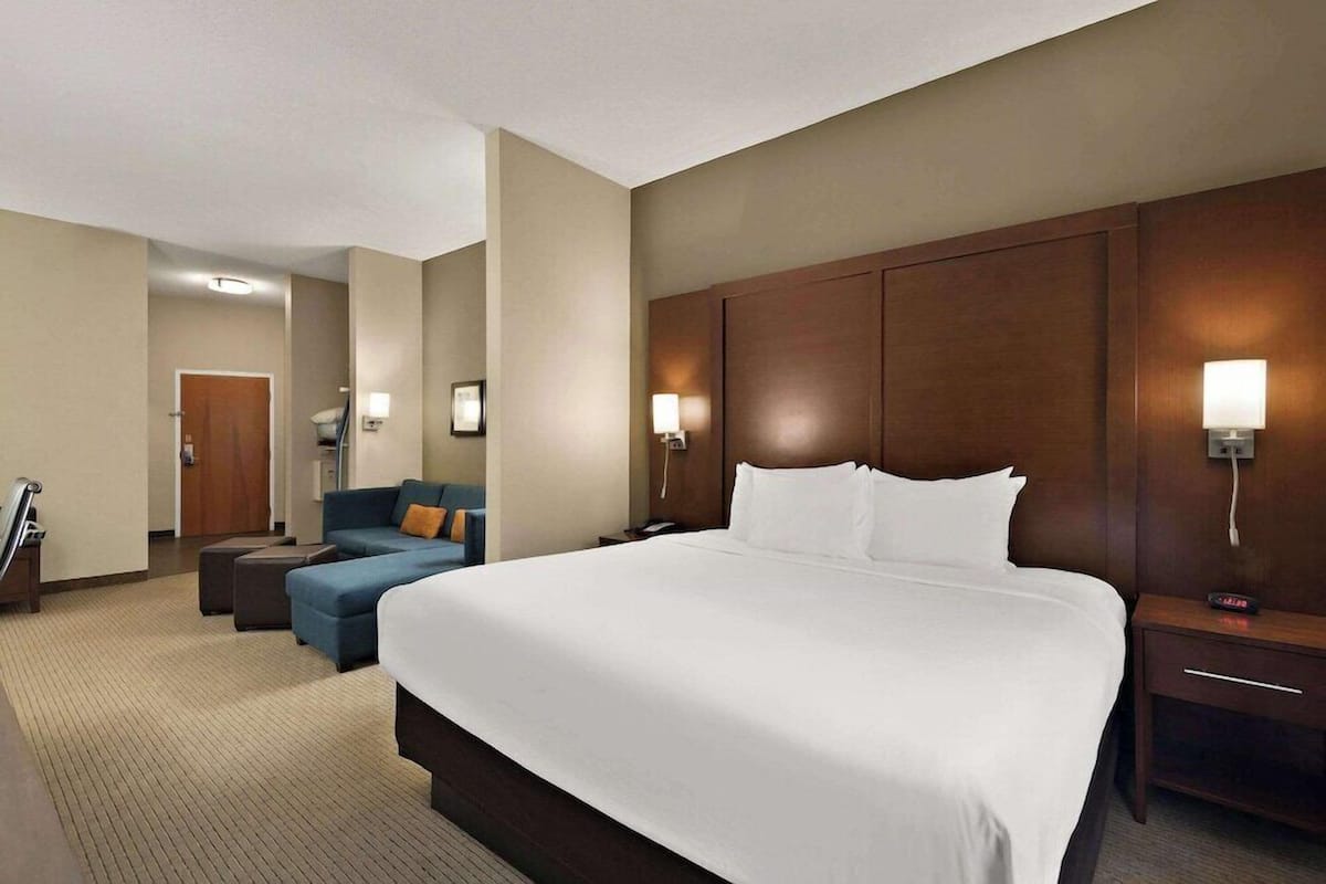 Une chambre d’hôtel avec un grand lit, un canapé, un bureau et une lampe.