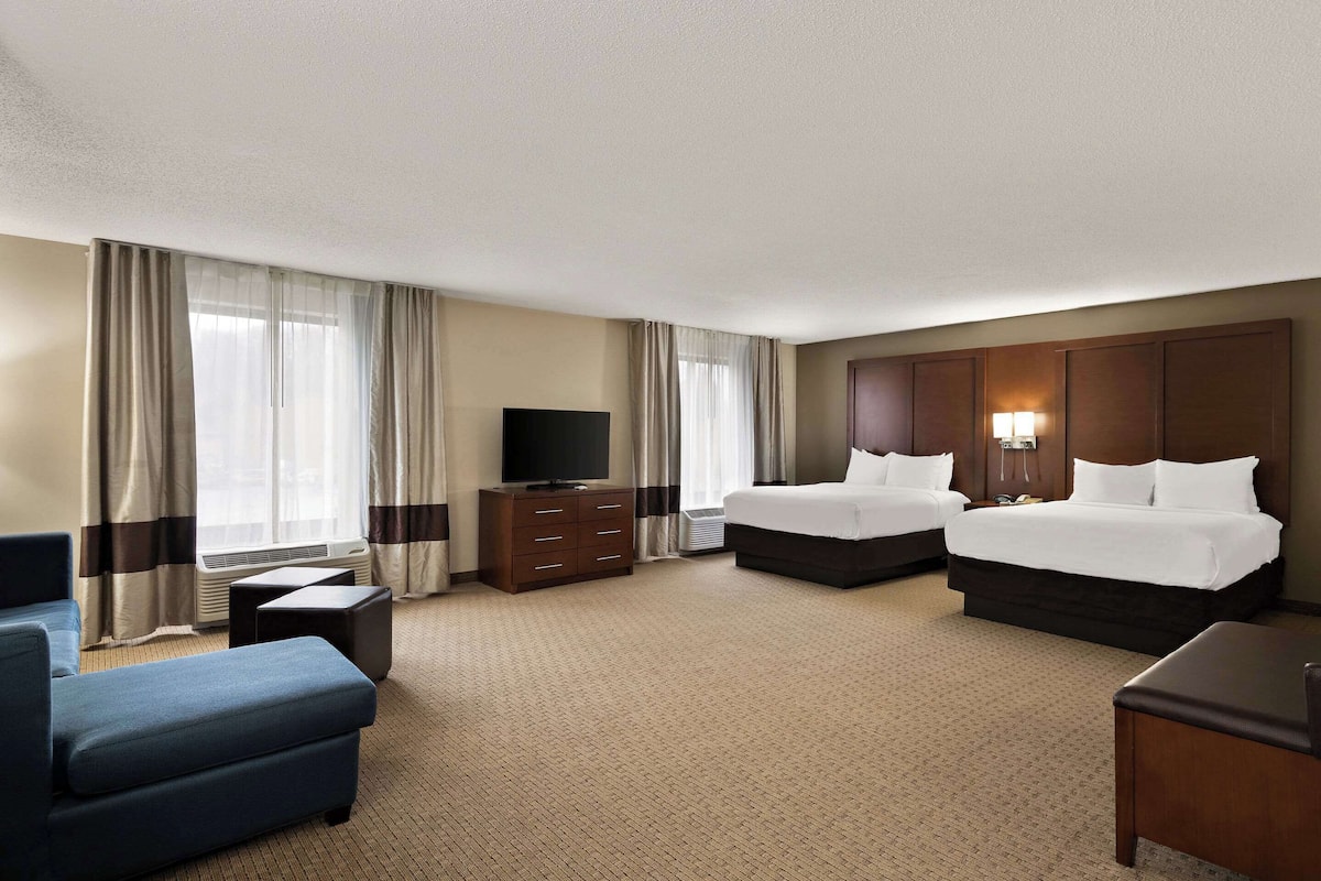 Une chambre d’hôtel avec deux lits, une télévision, un bureau et un canapé.