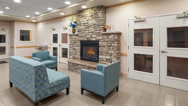 A lobby with a stone fireplace, blue upholstered seating, and a door with a window. - Days Inn by Wyndham Chino Valley (Chino Valley)