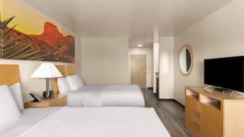 A hotel room with a bed, a desk with a lamp, a television, and a painting on the wall.