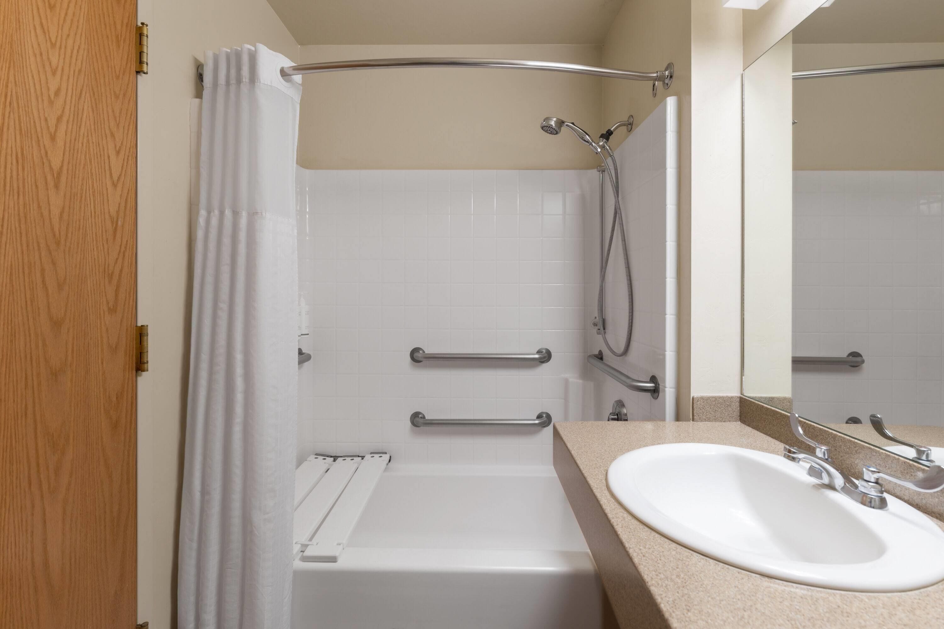 Un baño con bañera, ducha, lavamanos y espejo.