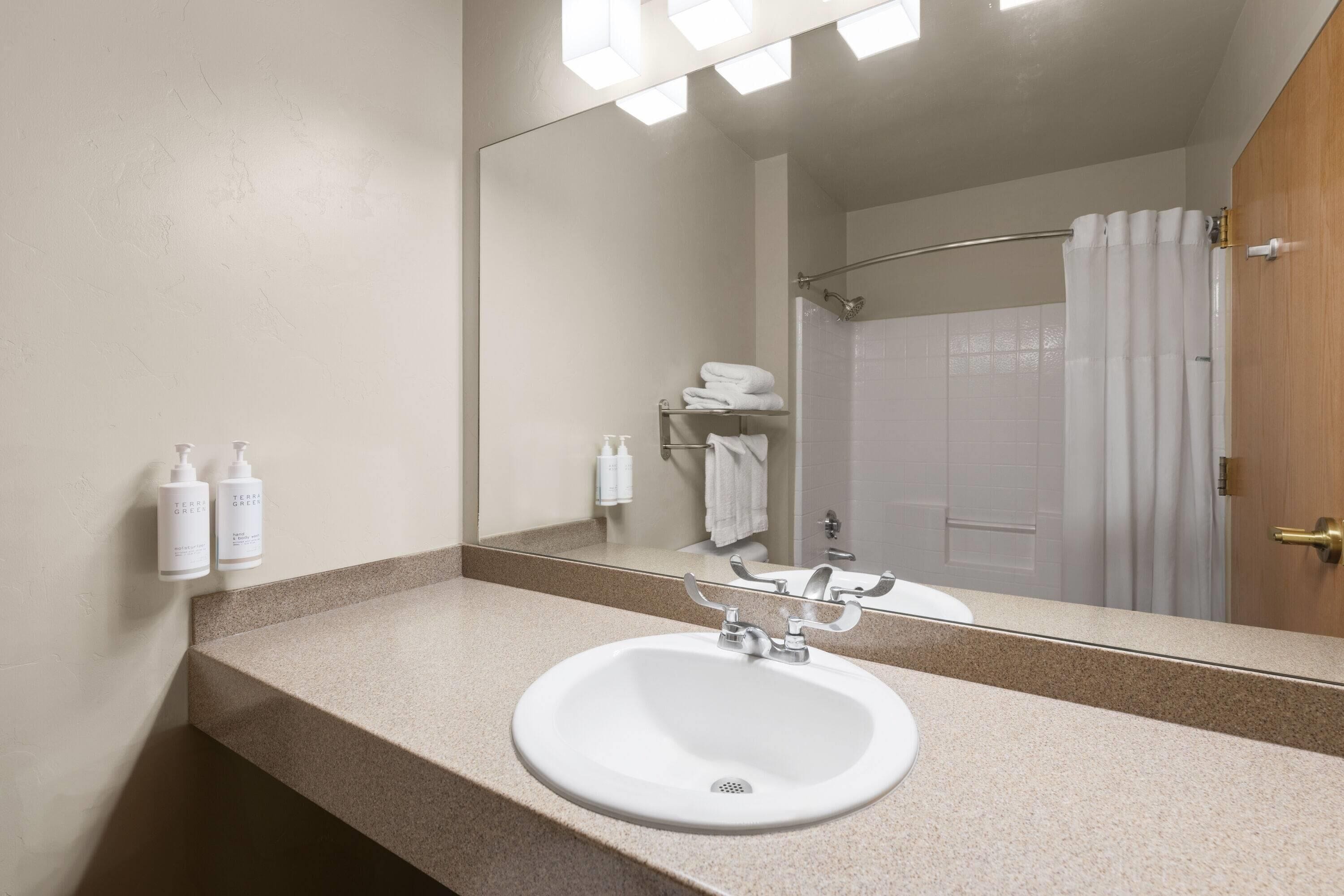Un baño con lavamanos, espejo y cortina de ducha.