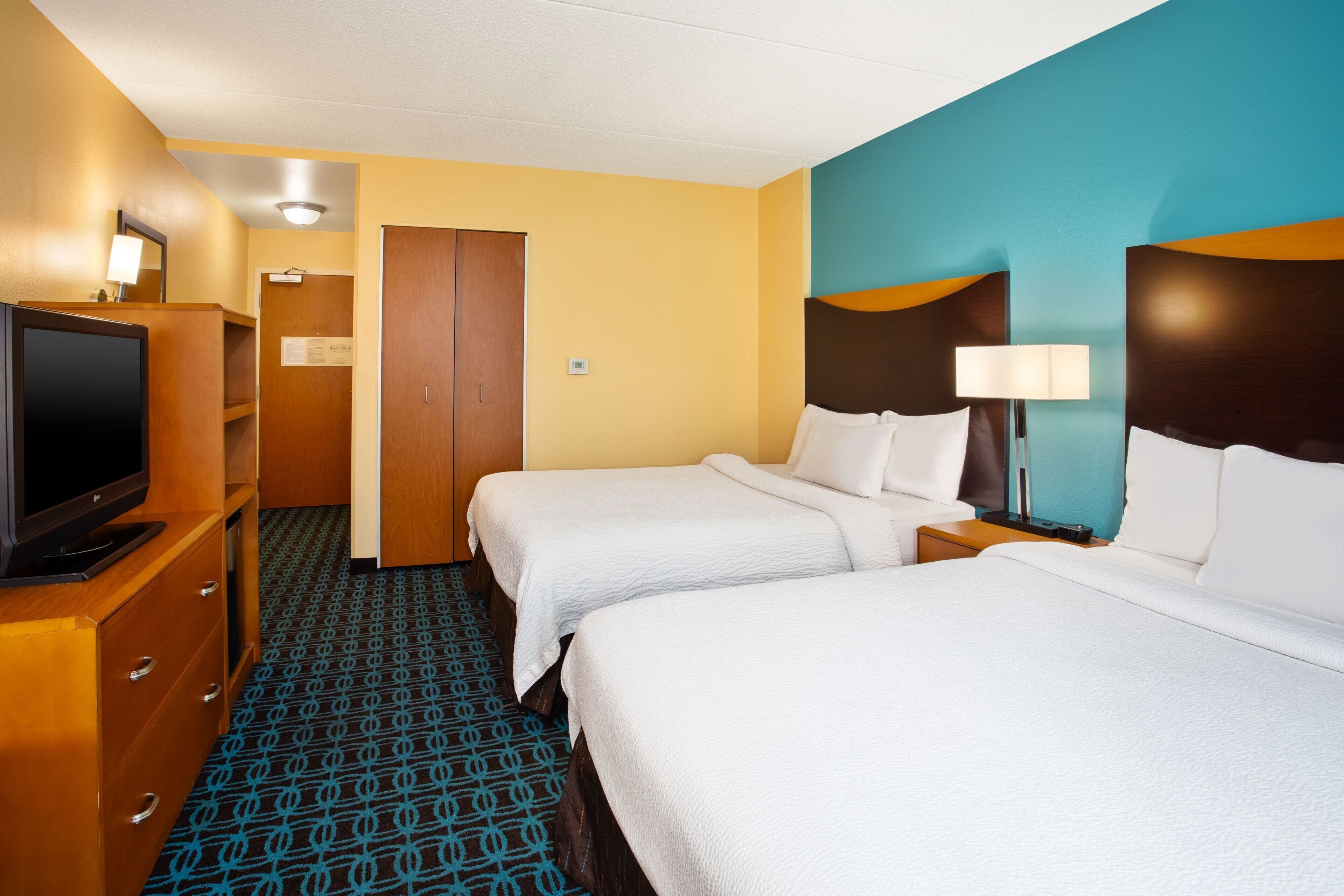 A hotel room with two beds, a television, a desk, and a wardrobe.