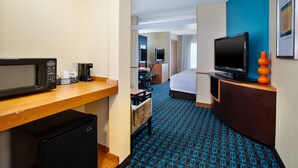 A hotel room with a kitchenette, a bed, a desk, a television, and a blue patterned carpet. - Fairfield Inn & Suites by Marriott Lexington North (Lexington)