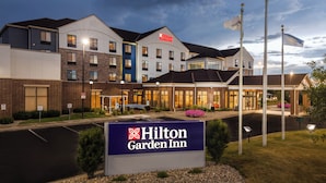 Un Hilton Garden Inn con un diseño de edificio moderno, múltiples accesos y una zona de entrada bien iluminada.