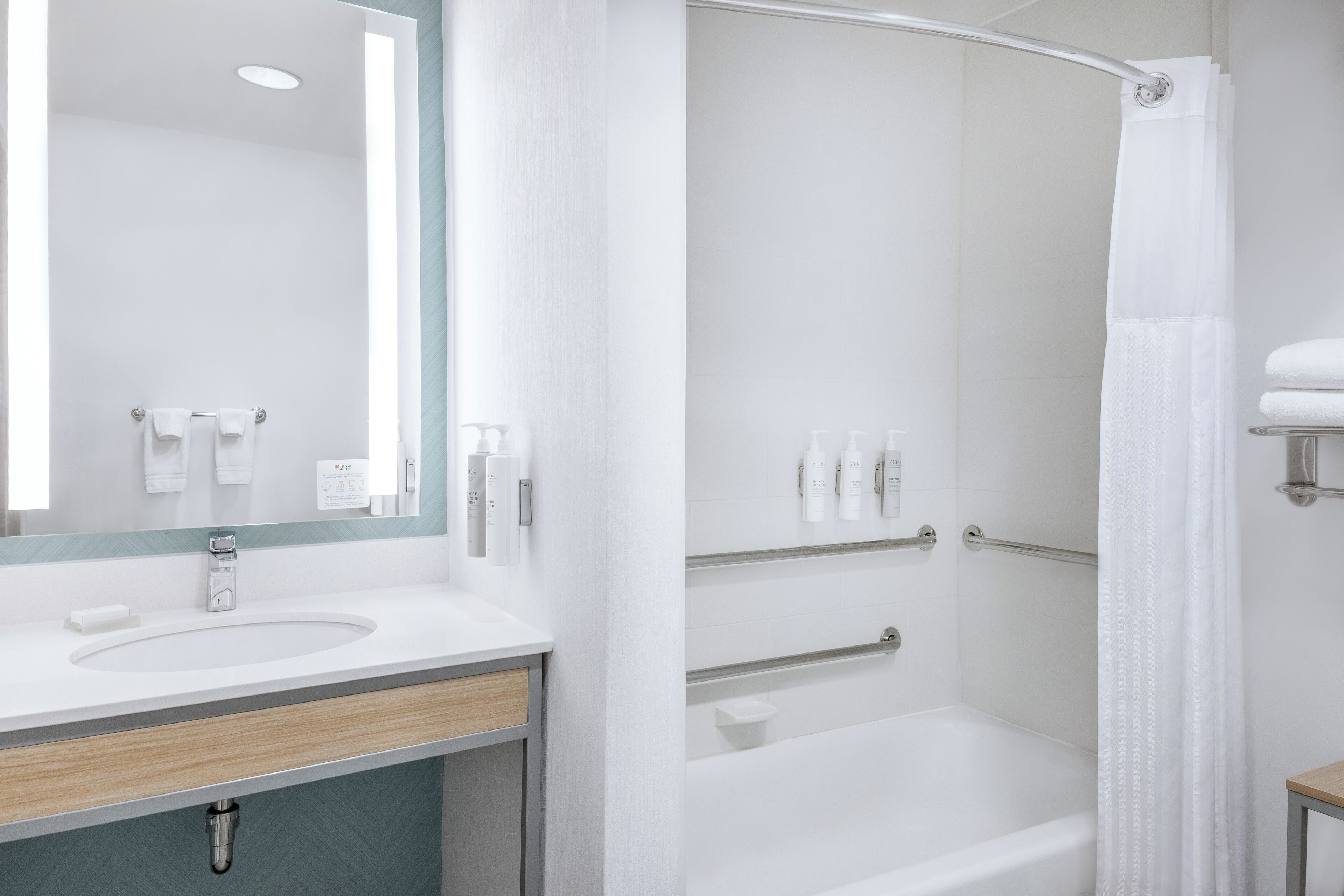 A modern bathroom with a sink, mirror, and shower area.
