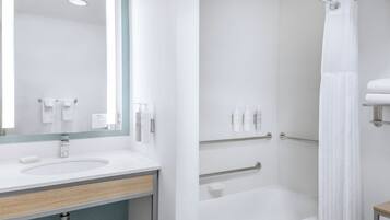 A modern bathroom with a sink, mirror, and shower area.