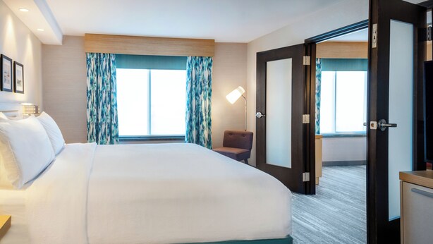 A hotel room with a large bed, a desk, a chair, and a television.