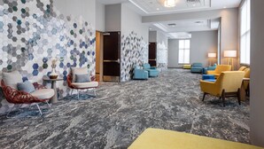 A hotel lobby with hexagonal mosaic walls, a marble-patterned floor, and a mix of modern and classic seating.