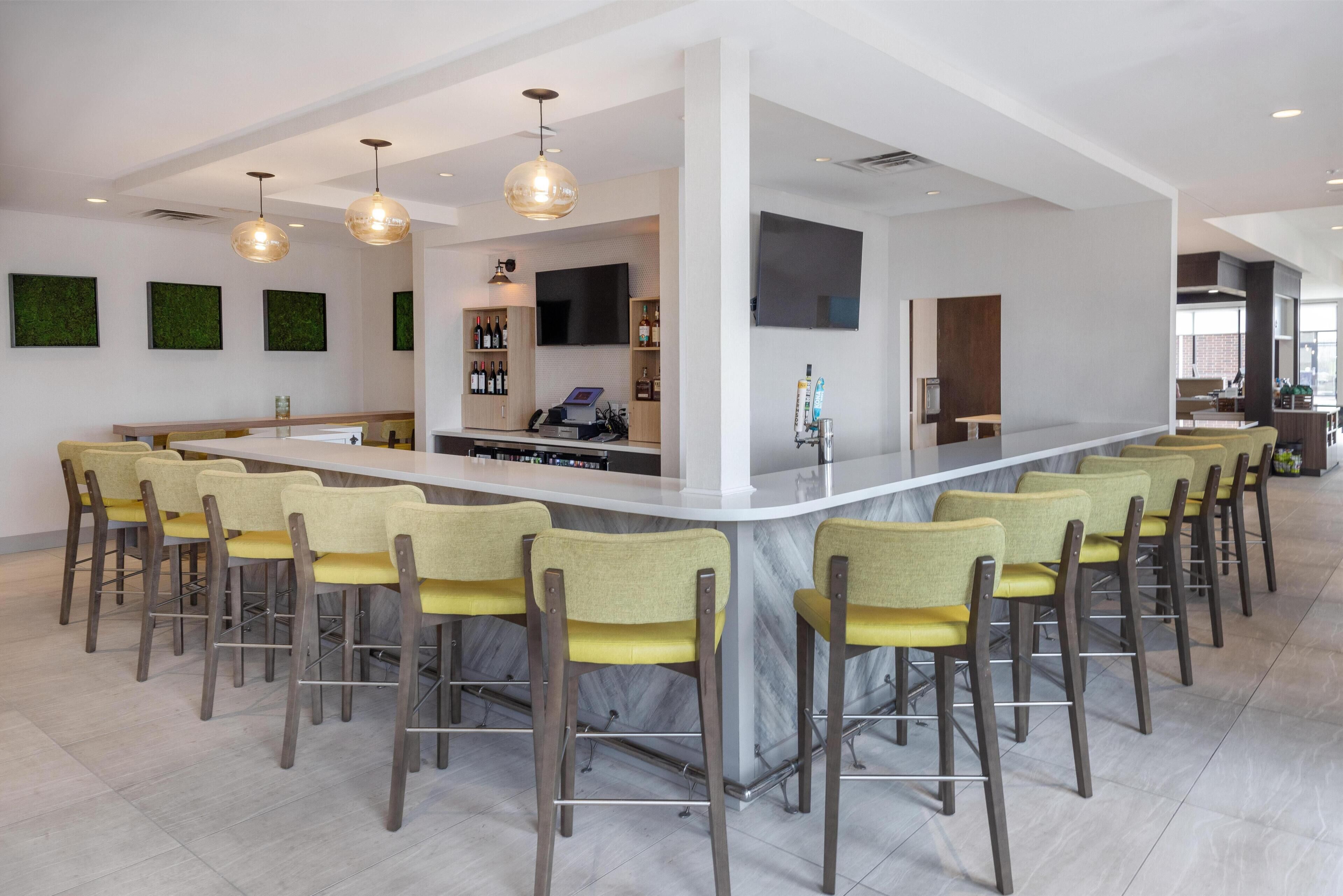 A modern kitchen with a central island, bar stools, and pendant lighting.