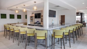 A modern kitchen with a central island, bar stools, and pendant lighting.