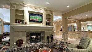 A spacious lobby with a fireplace, a television mounted above it, and a patterned carpet. - Hilton Garden Inn Mount Holly/Westampton (Mount Holly)