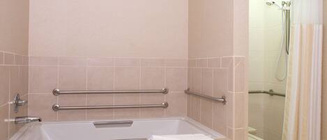 A bathroom with a bathtub, grab bars, and a shower area.